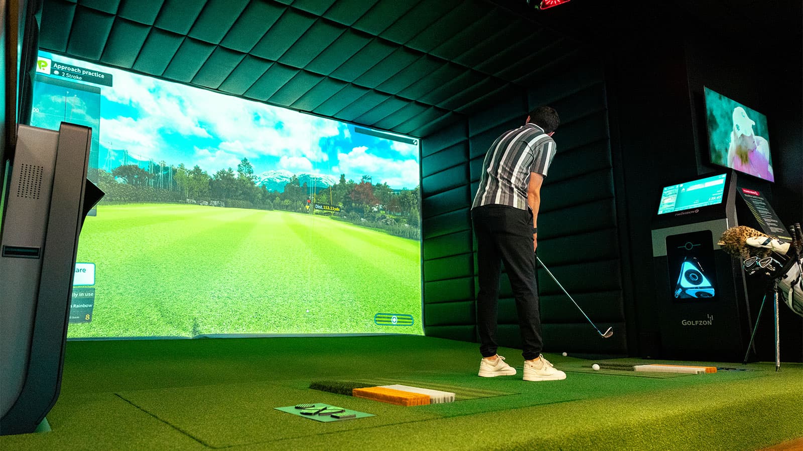 Player at an indoor golf simulator bay with screen projection